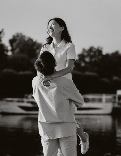 One partner lifts the other during their couple photoshoot beside the Seine.