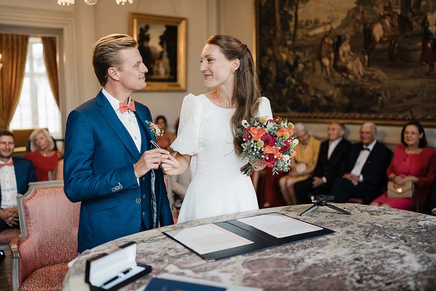 Les mariés échangent un regard près du registre de mariage, devant leurs proches.